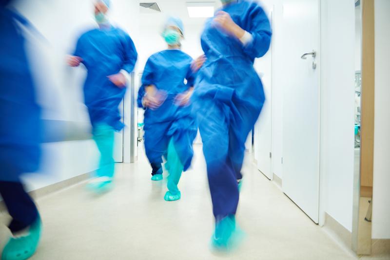 hospital staff running down a corridor wearing masks and scrubs