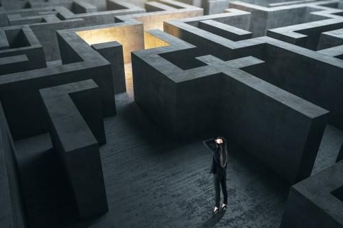 Young businesswoman in suit standing in concerete gray labyrinth.